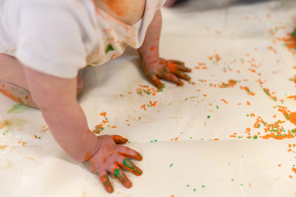 baby-crawling-on-paper-with-messy-hands-covered-in-paint