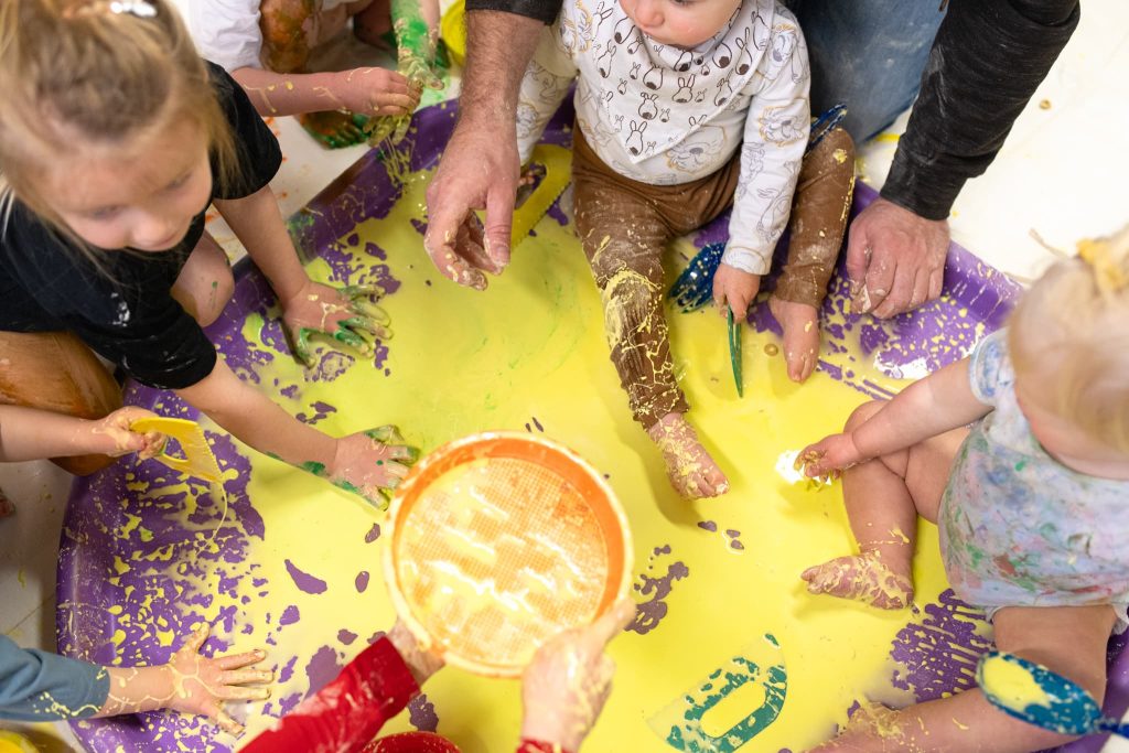 babies-and-children-sitting-in-paint-feeling-with-hands