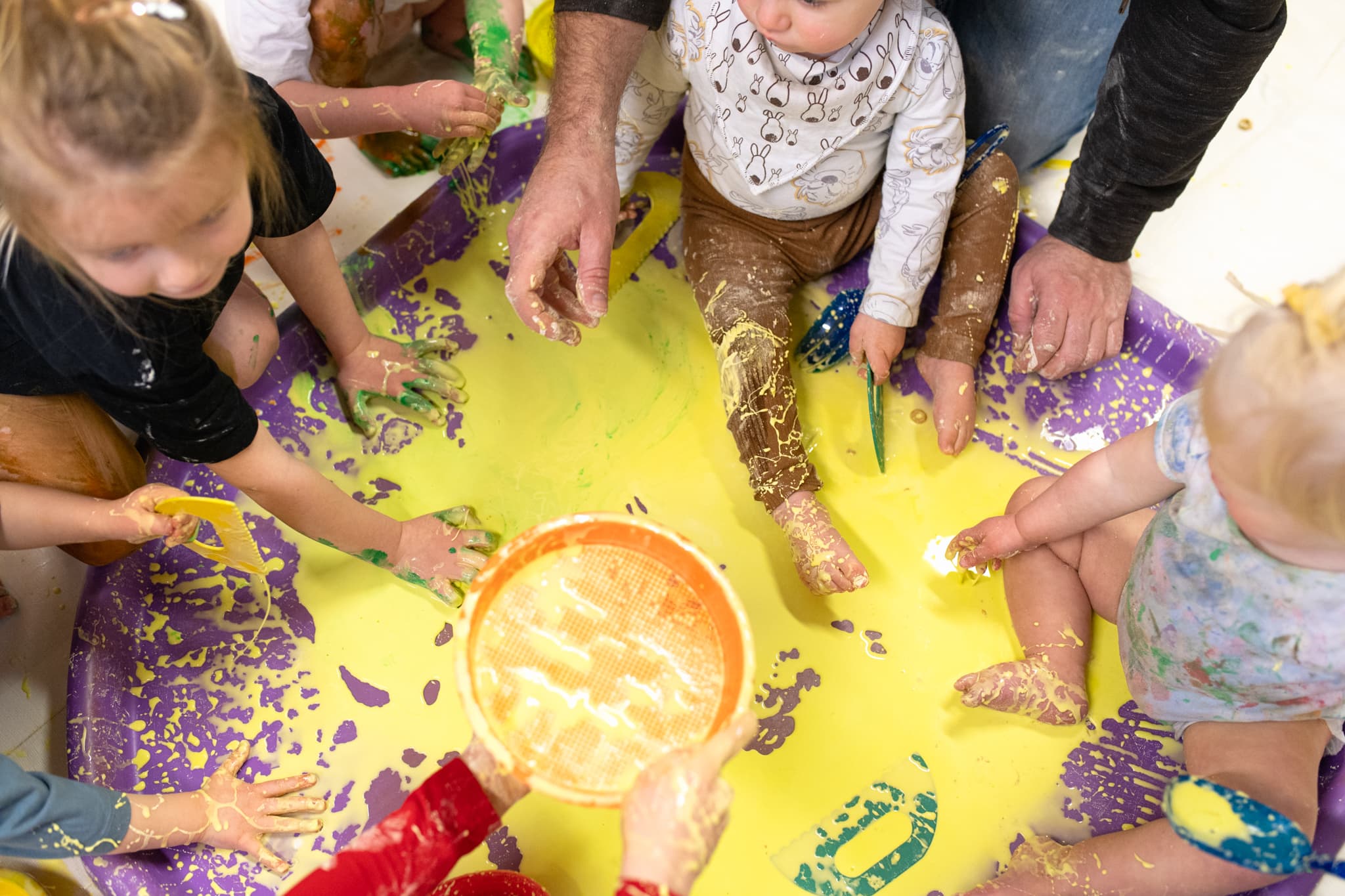 babies-and-children-sitting-in-paint-feeling-with-hands