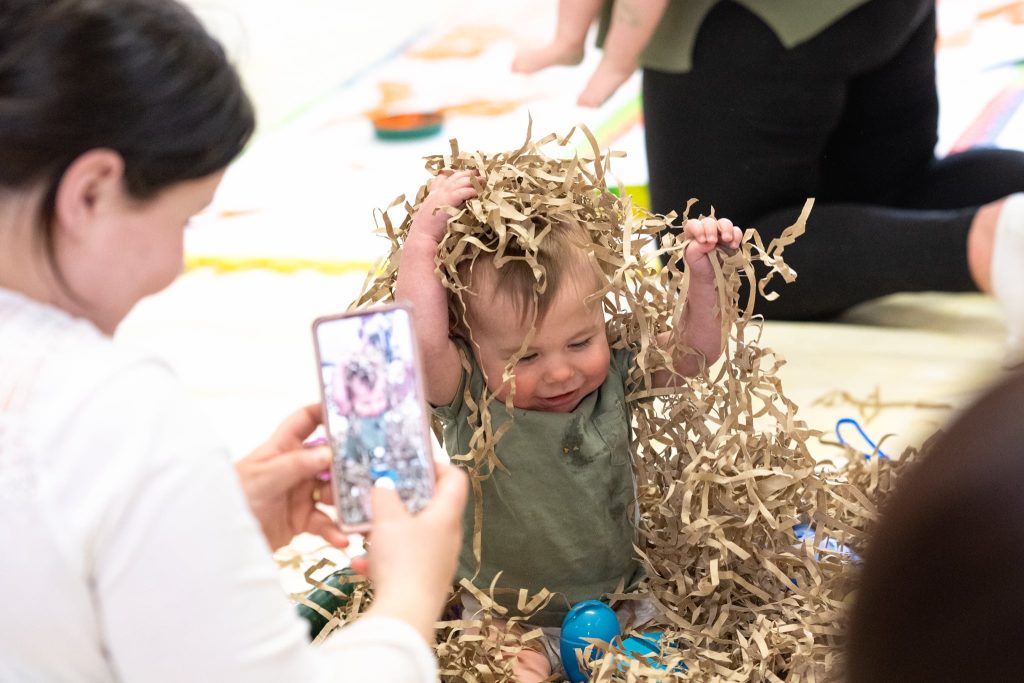 class-smiling-baby-playing-with-paper-stripes