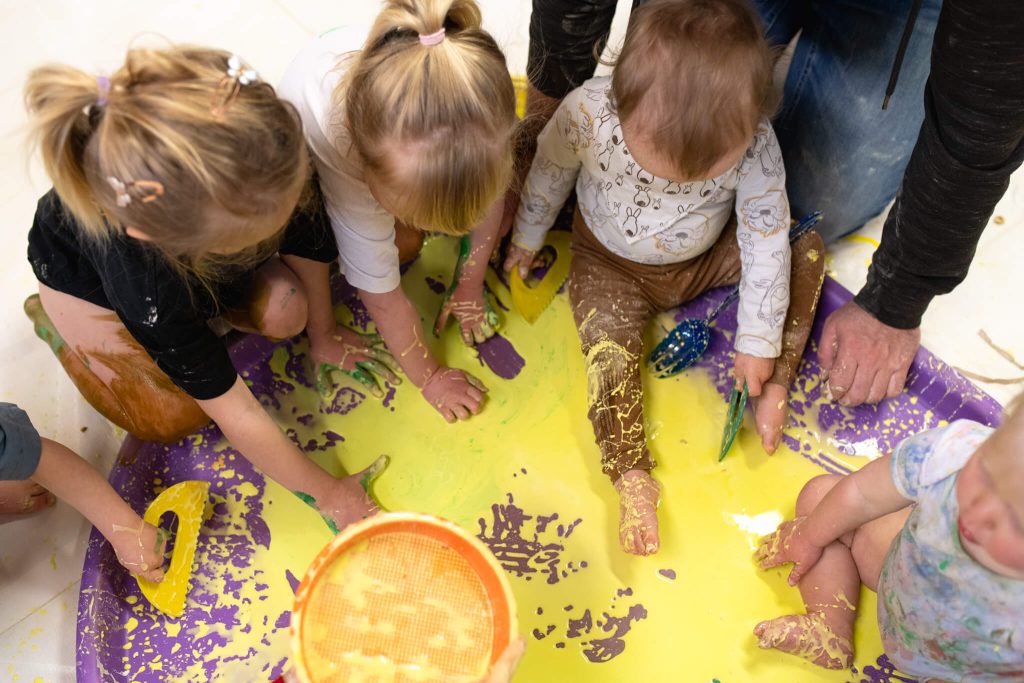babies-and-children-sitting-in-paint-feeling-with-hands