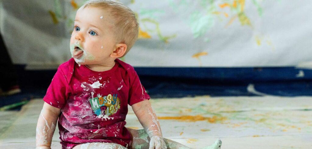 messy child covered in paint at a messy play class
